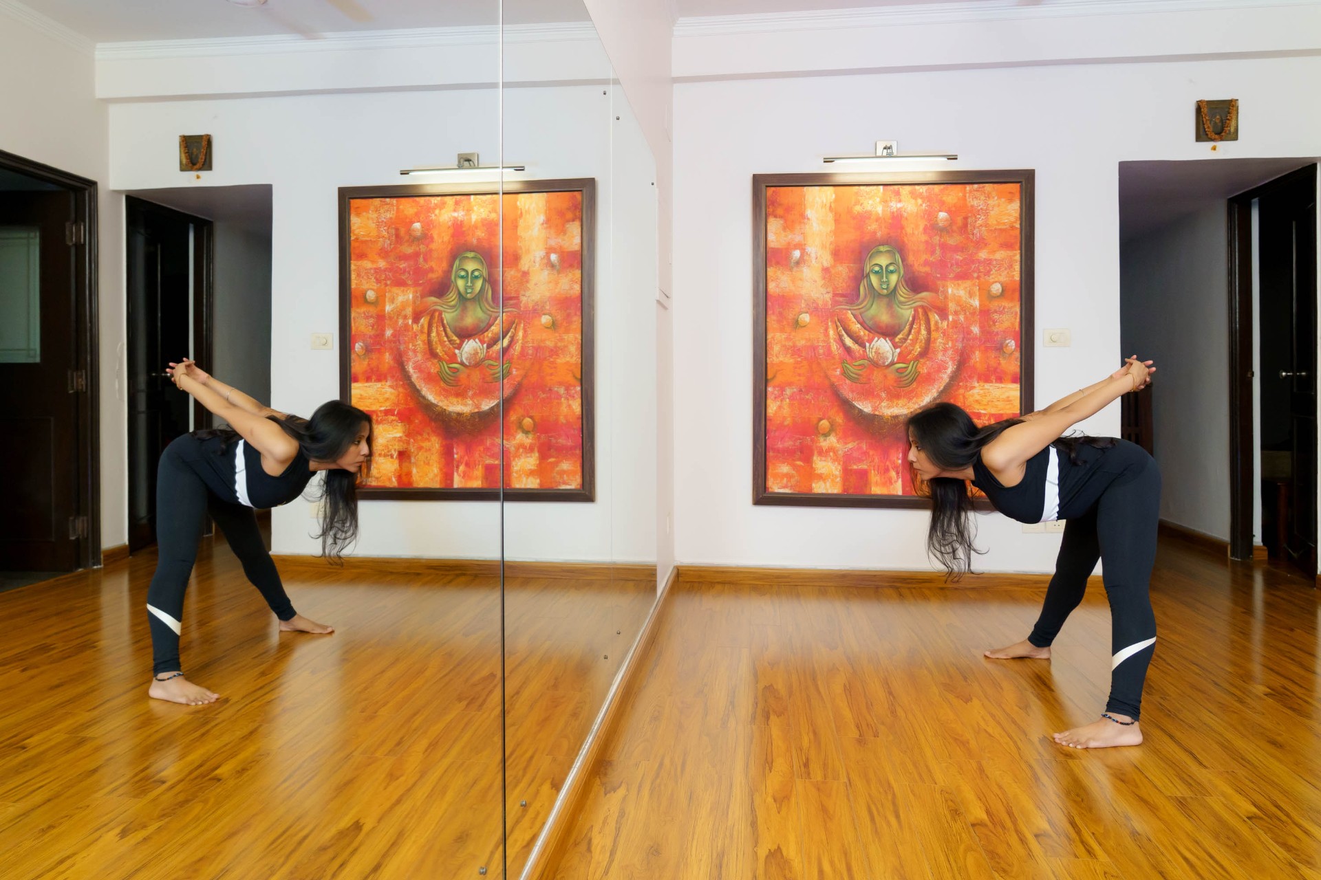 Pallavi in extended-angle pose, mirrored before the lotus painting
